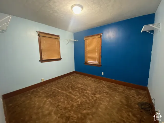 Room featuring two windows with wood-finish blinds, wall-mounted shelving, and wood trim accents
