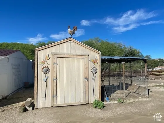 Storage shed with a pitched roof and a metal rooster weather vane