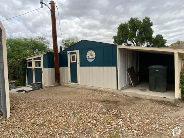 Two-tone storage shed with window, side access door, and attached carport with concrete pad