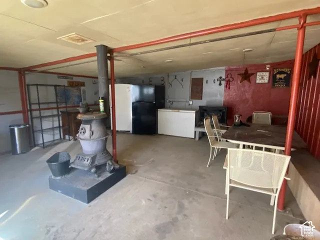 Concrete flooring with an antique wood-burning stove, red accent wall, and exposed structural beams. Great for entertaining.  This room also has a propane fireplace.