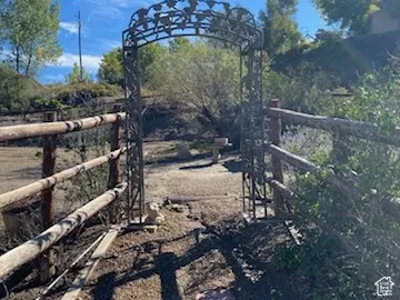Decorative metal archway with intricate detailing, flanked by rustic wood fencing