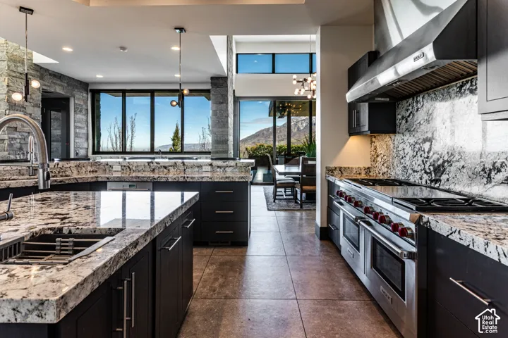 Gourmet kitchen with stainless steel appliances, dark wood cabinetry, light-toned stone countertops, and a stone backsplash