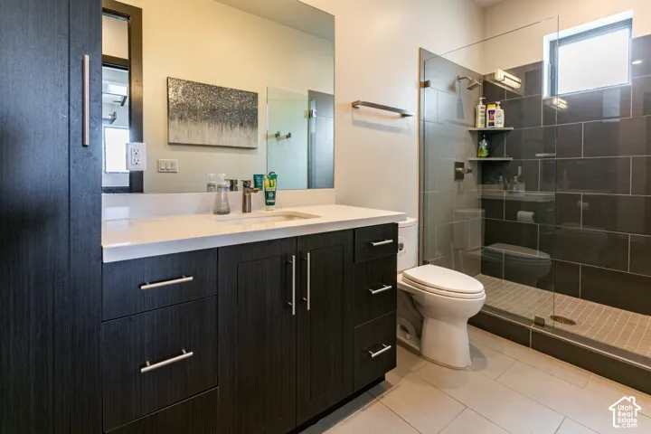 Dark wood-finish cabinetry, white countertop, and a built-in shower with dark tile surround and glass enclosure