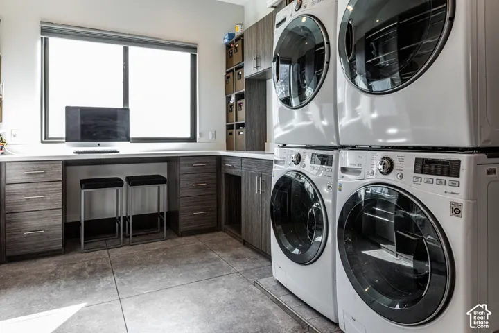 Integrated laundry facilities with stackable washer and dryer units, extensive built-in cabinetry, substantial counter space, and durable tile flooring