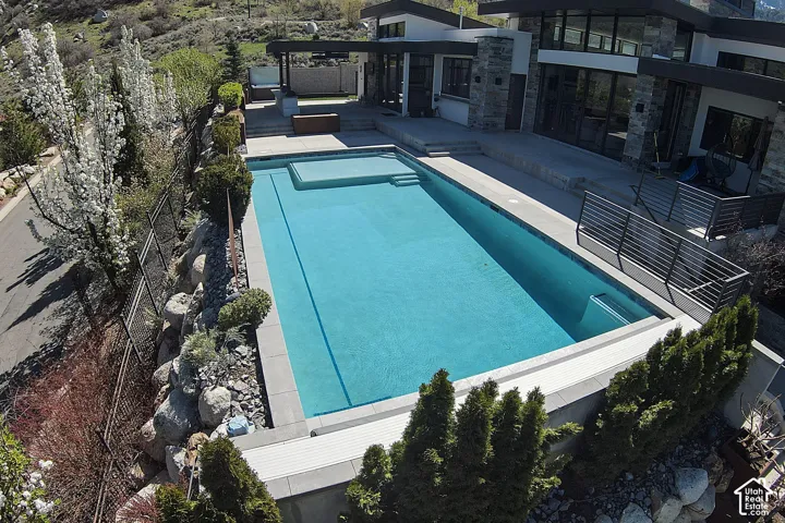 Expansive outdoor pool with integrated spa, surrounded by a concrete patio