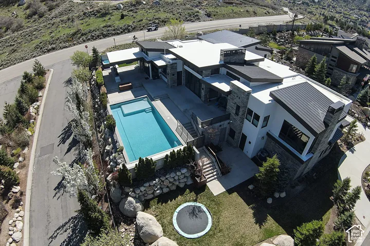 Contemporary architecture featuring a multi-level design, stone cladding, a swimming pool, and a manicured lawn