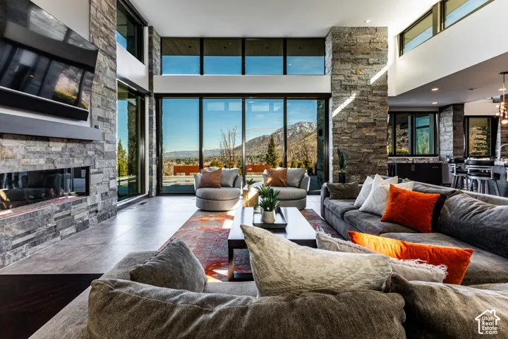 Expansive living area featuring a floor-to-ceiling stone fireplace, large format tile flooring, and a double-height ceiling