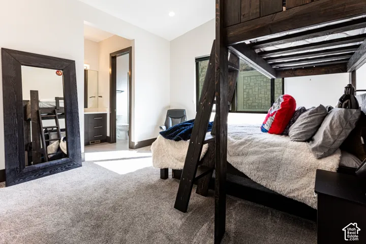 Built-in wood-finish bunk bed frame, integrated lighting, plush carpeting, and an adjoining bathroom featuring a vanity with under-sink storage