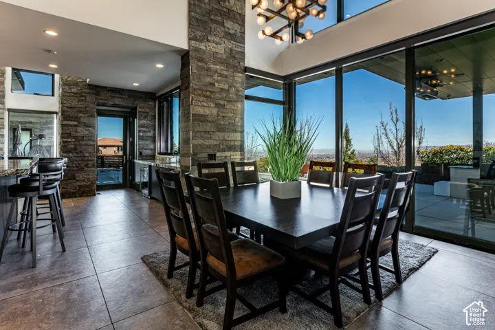 Floor-to-ceiling glass doors, stone accent walls, recessed lighting, tile flooring, and a contemporary chandelier