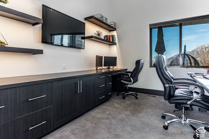 Built-in custom cabinetry with dark wood-finish, integrated floating shelves with recessed lighting, and a large window with mountain scenery