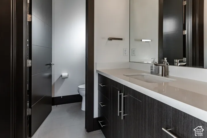 Vanity with integrated sink, brushed nickel faucet, large wall mirror, and dark wood-finish cabinetry with silver hardware