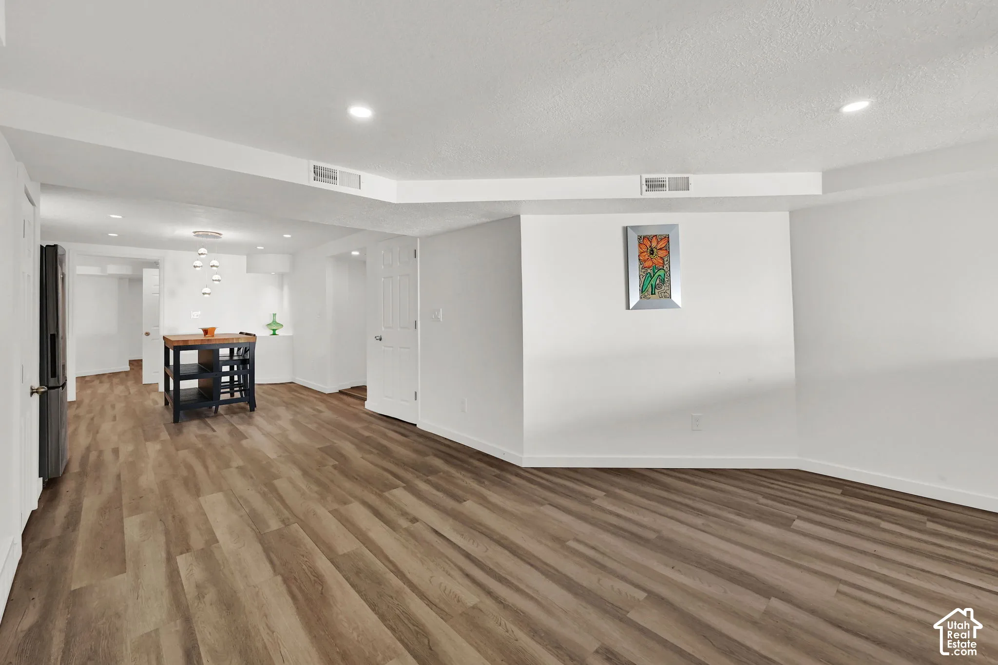 Recessed ceiling lighting, wood-finish flooring, white walls, and a built-in kitchen island with a wood countertop