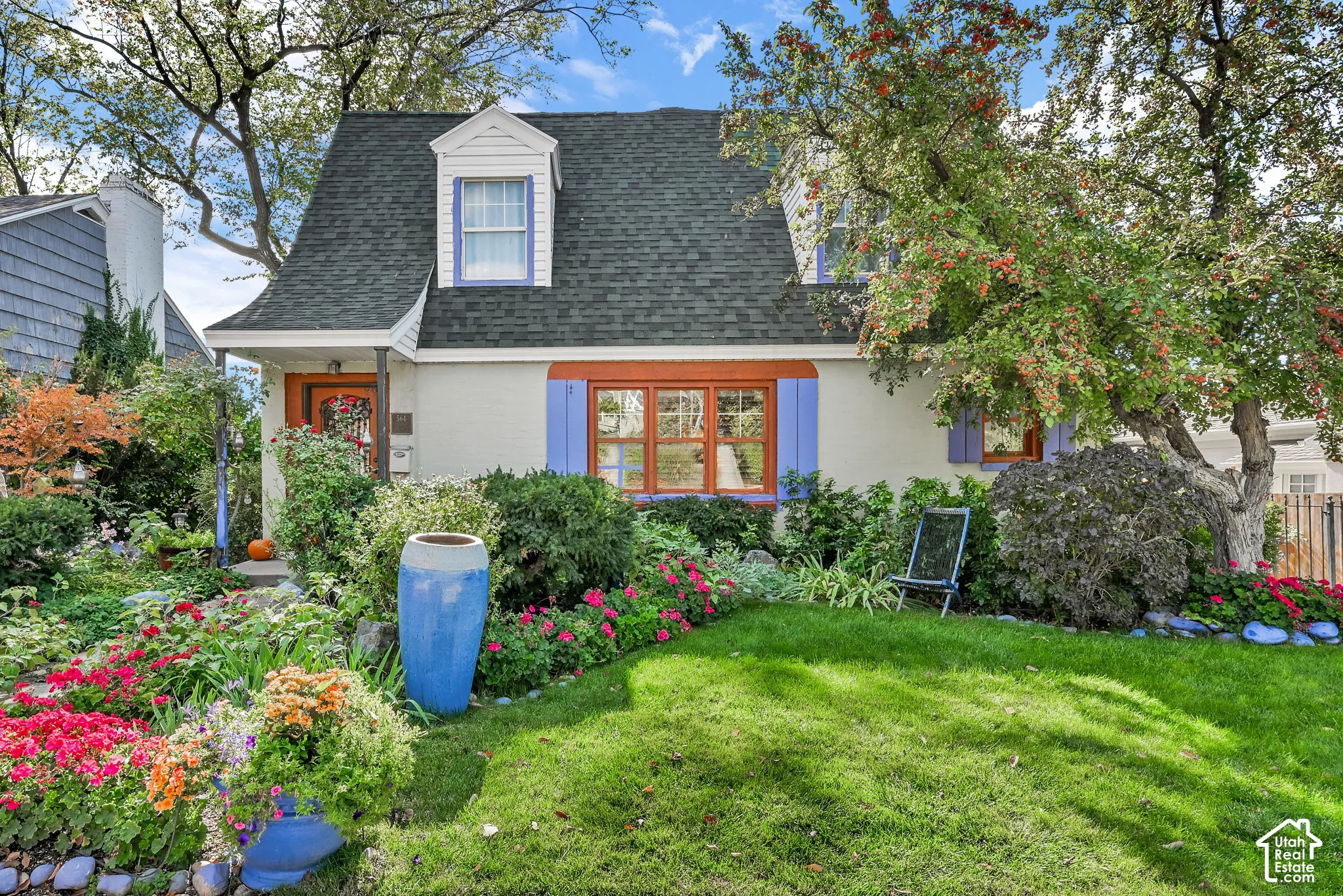 White stucco exterior with a dark shingle roof, purple window shutters, and a front dormer