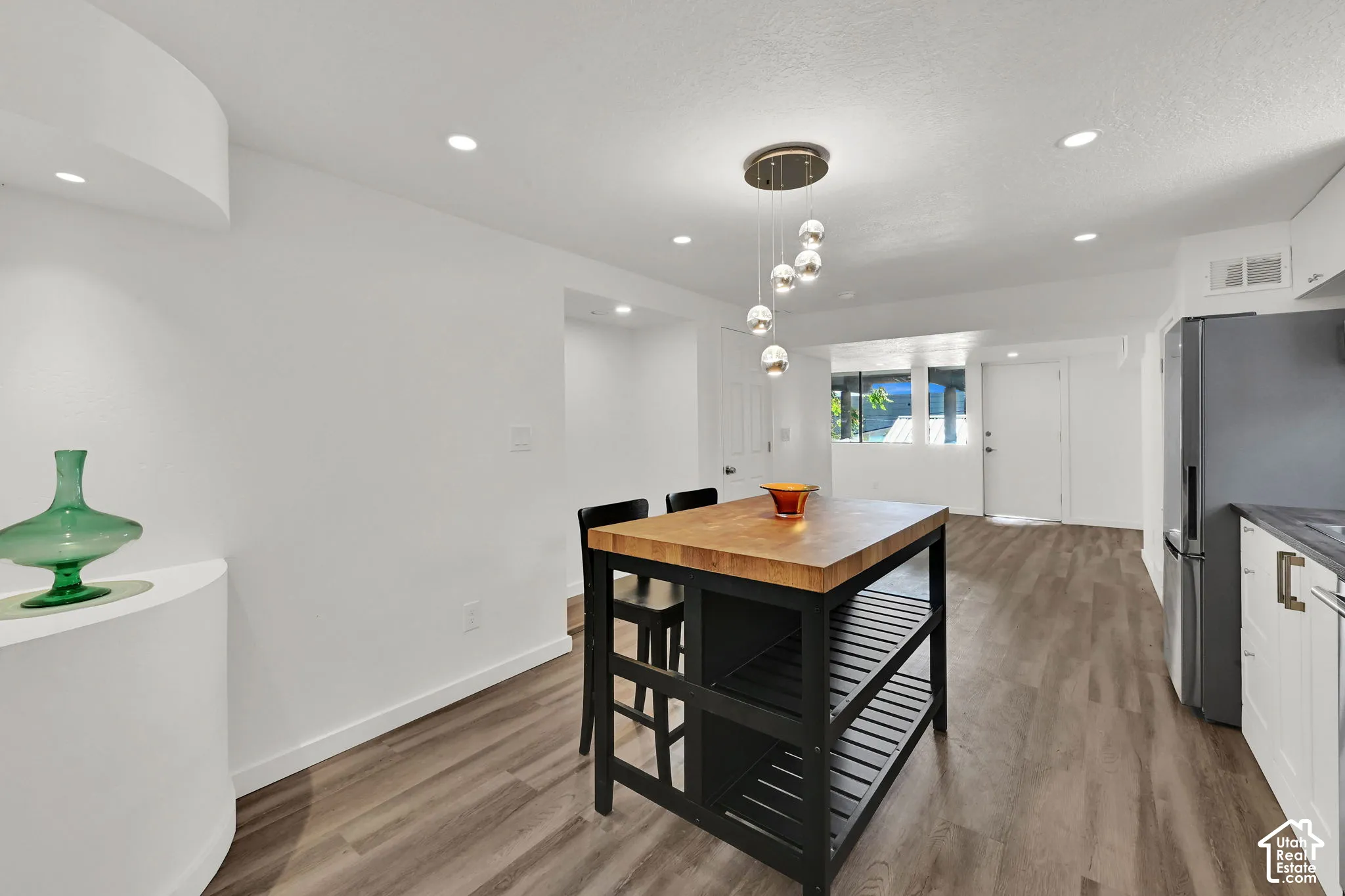 Wood-finish flooring with a modern island featuring a butcher block countertop and integrated shelving