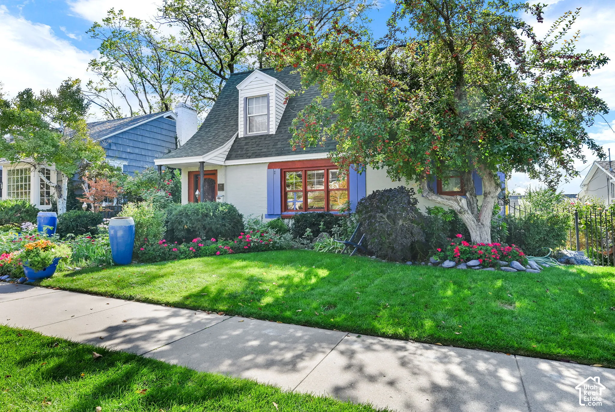 Gable dormer with white siding, blue shutters, and a front entry with a covered porch