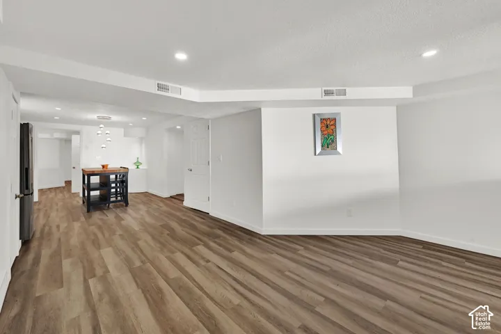 Recessed ceiling lighting, wood-finish flooring, white walls, and a built-in kitchen island with a wood countertop