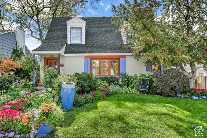 White stucco exterior with a dark shingle roof, purple window shutters, and a front dormer