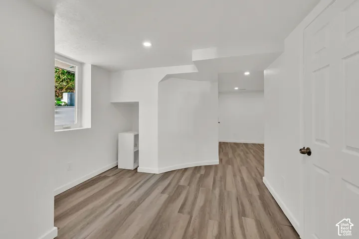 Recessed lighting illuminates the wood-finish flooring, complemented by crisp white walls and trim