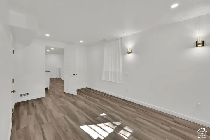 Wood-finish flooring, recessed lighting, and wall-mounted sconces illuminate this interior space