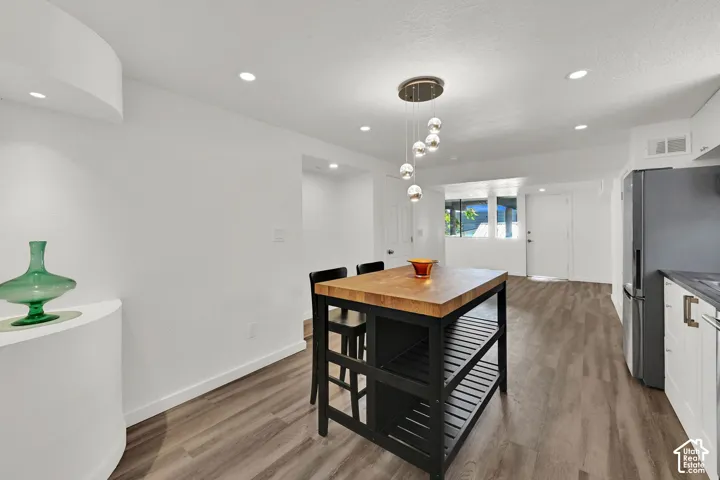 Wood-finish flooring with a modern island featuring a butcher block countertop and integrated shelving