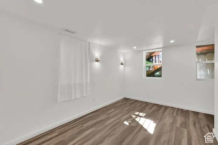 White walls, wood-finish flooring, recessed lighting, and wall-mounted sconces