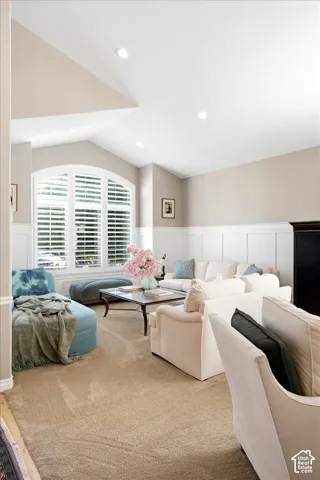 Vaulted ceiling with recessed lighting, arched window with plantation shutters, wainscoting, and neutral-toned carpet flooring