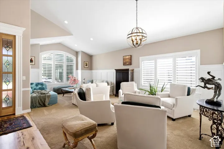 Vaulted ceiling with recessed lighting, decorative chandelier, arched window, and board and batten wall paneling