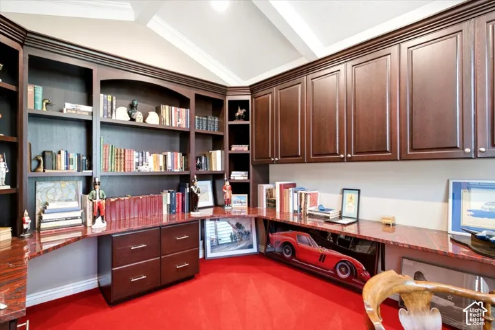 Built-in wood cabinetry, integrated shelving, wood-finish desk, and a vaulted ceiling