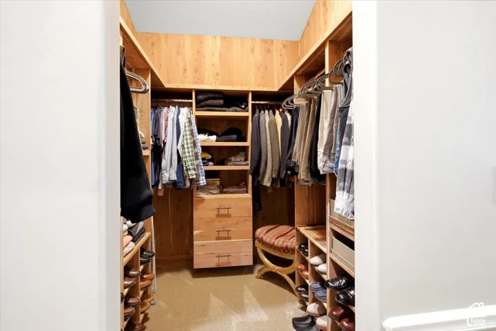 Walk-in closet featuring wood-finish cabinetry, built-in shelving, integrated hanging rods, and three built-in drawers