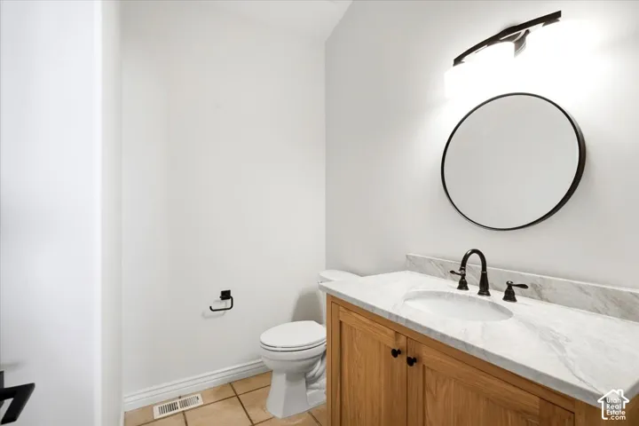 Wood-finish vanity cabinet with black hardware, white rectangular under-mount sink, and light-toned stone countertop