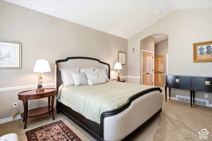 Vaulted ceiling, arched doorway, light wood-finish doors, and wall molding details