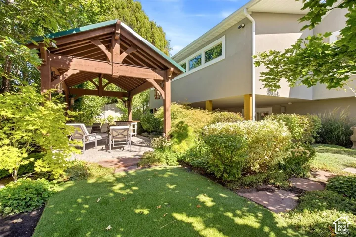 Expansive lawn with a stone pathway, shaded pergola over a paver patio, and mature landscaping