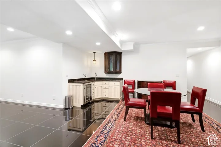 Wet bar with stone countertop, white shaker-style cabinetry, and integrated beverage refrigerator