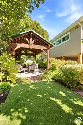 Expansive outdoor space featuring a wooden pergola, artificial turf, and a stone patio