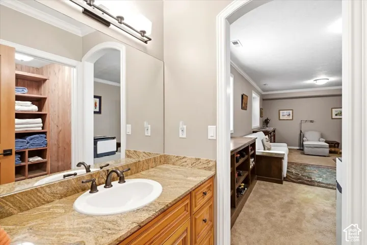Wood-finish vanity with an oval undermount sink, bronze-finish faucet, and granite-style countertop