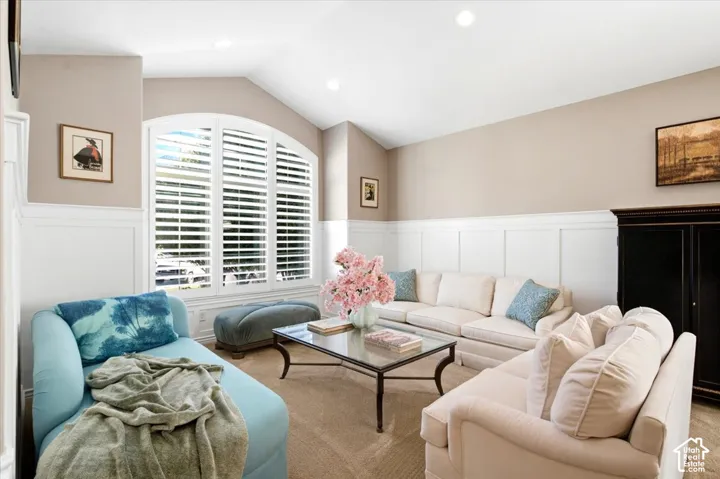 Vaulted ceiling with recessed lighting, arched window with plantation shutters, wainscoting, and carpet flooring