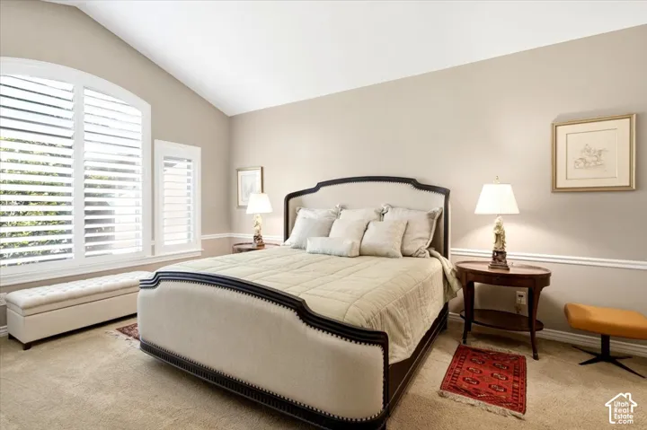 Vaulted ceiling with an arched window, white plantation shutters, and crown molding