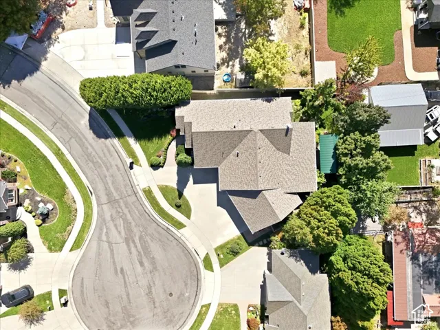 Large residential lot with mature trees, established landscaping, and a curvilinear paved driveway