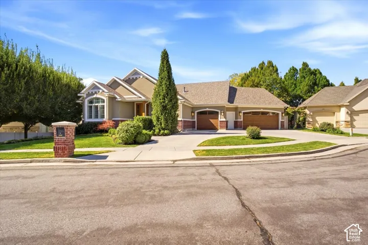 Stucco exterior with stone accents, arched garage doors, brick-clad mailbox, and a curved concrete driveway