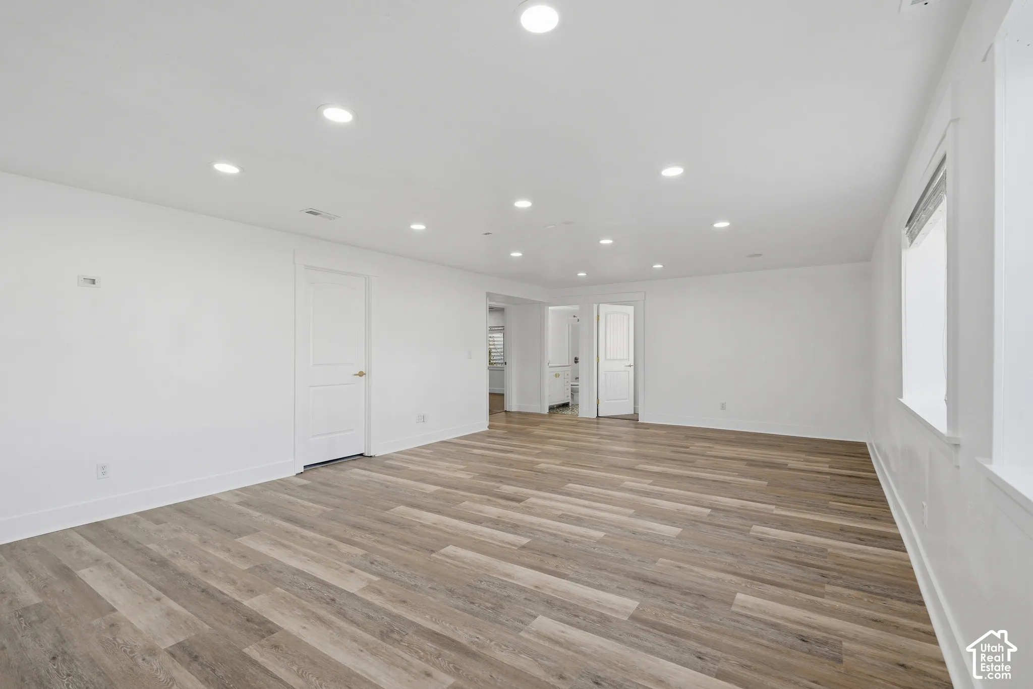 Recessed ceiling lighting, wood-finish flooring, white painted walls, and white trim