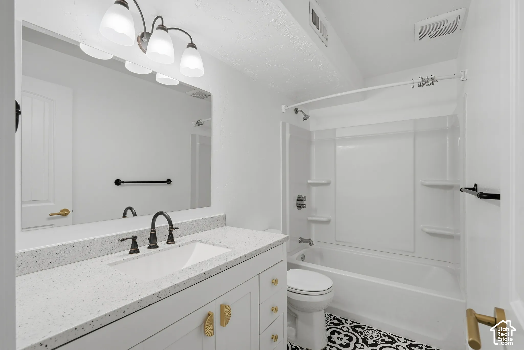 Vanity with a white countertop and integrated sink, bronze-finish faucet, and gold-tone hardware