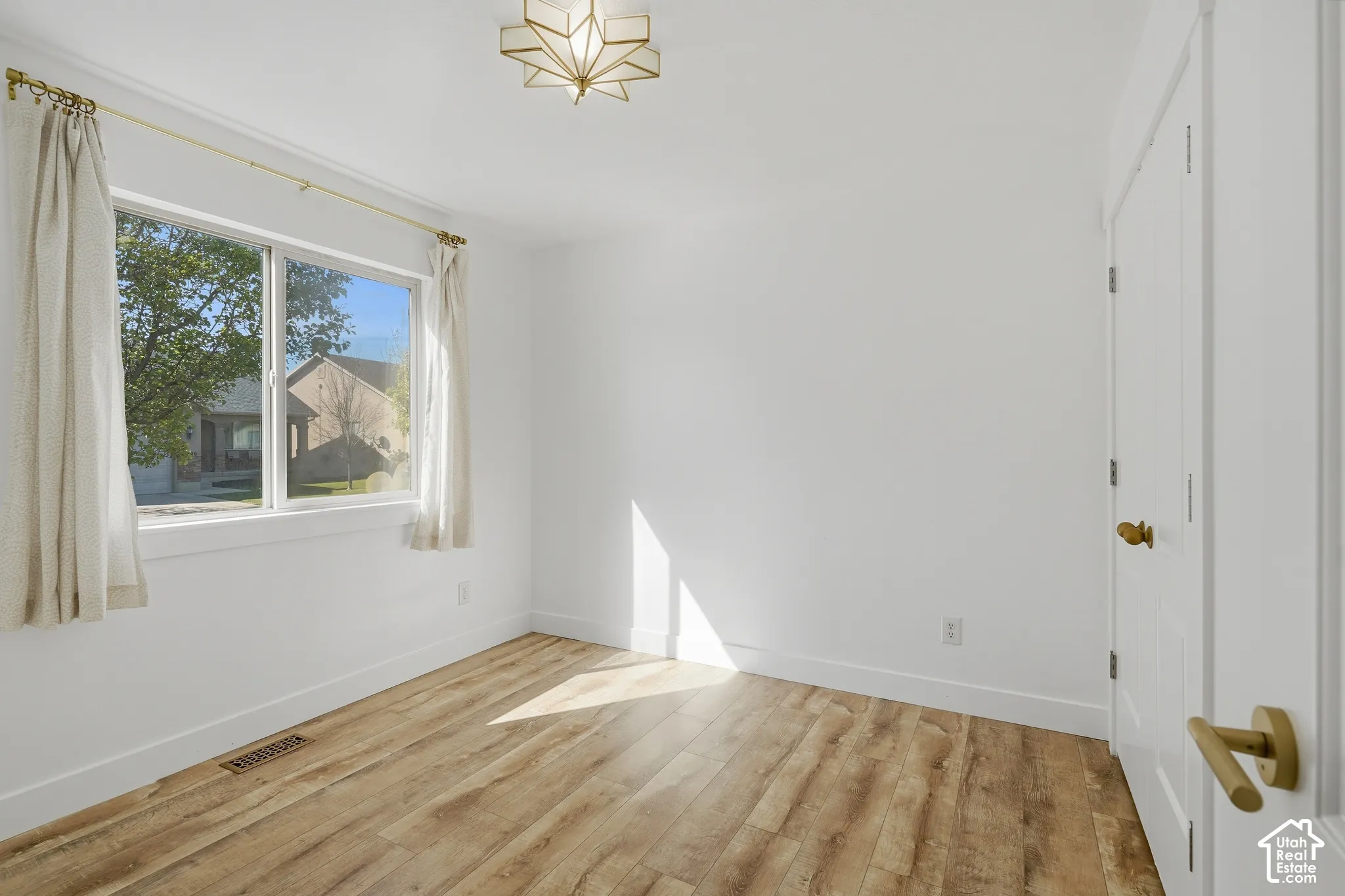 Wood-finish flooring, white walls, white trim, and a decorative ceiling light fixture