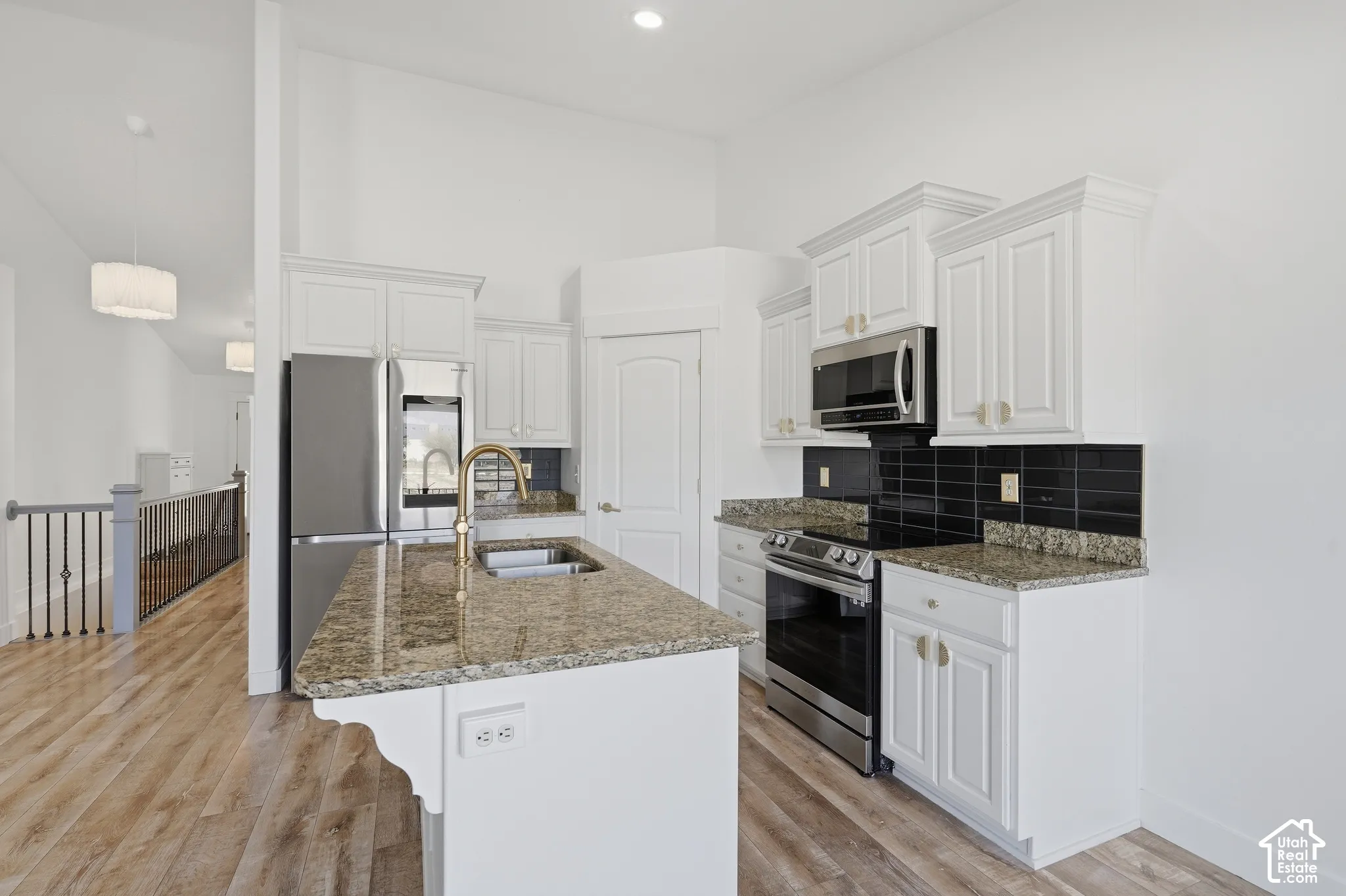 Modern kitchen featuring white cabinetry, stainless steel appliances, and a large granite-topped island with seating