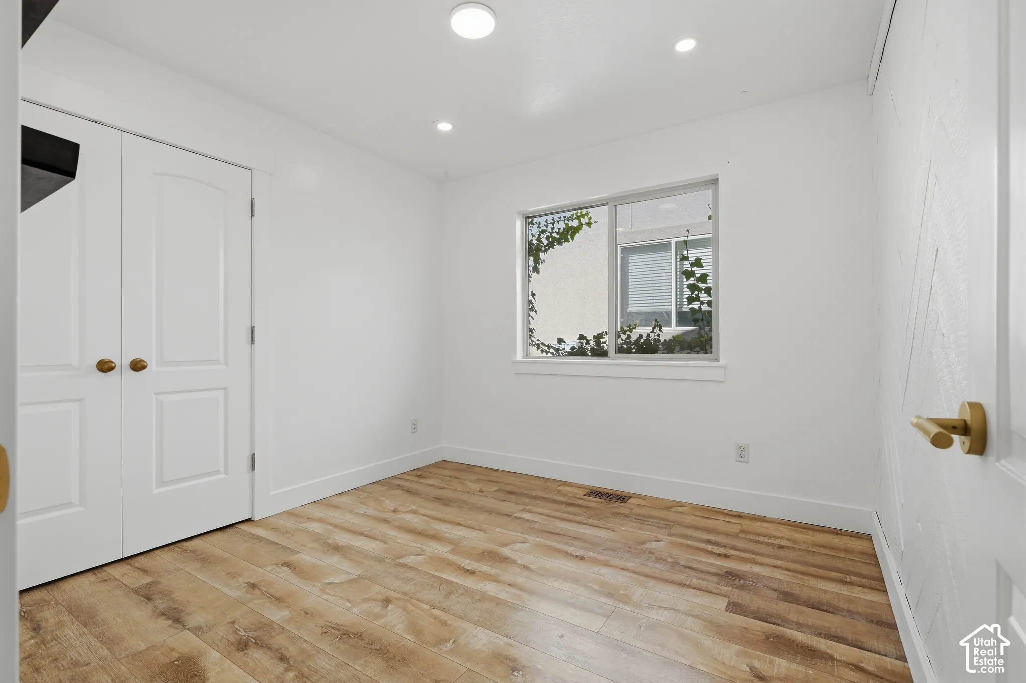 Wood-finish flooring, recessed lighting, double-door closet, and a window with white trim
