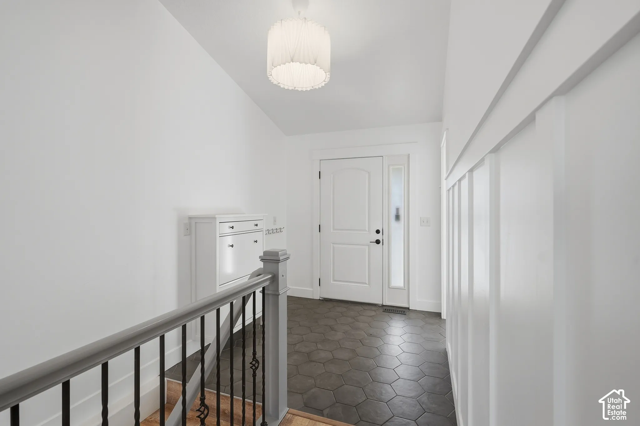 Entryway featuring hexagonal floor tiles, board and batten wall detailing, a white paneled door with sidelight, and an overhead drum light fixture
