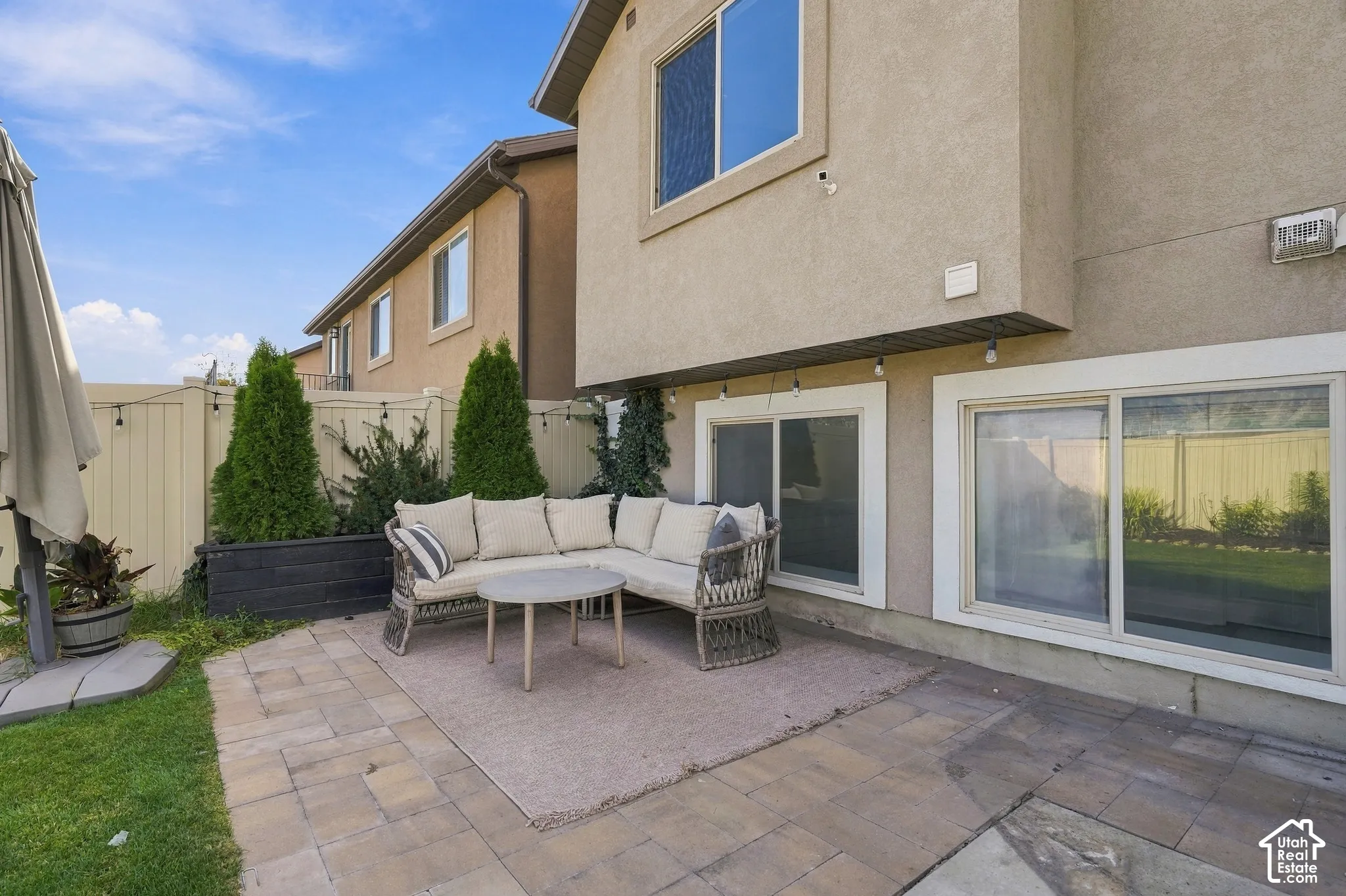 Private patio featuring paver stone flooring, string lighting, and raised planters