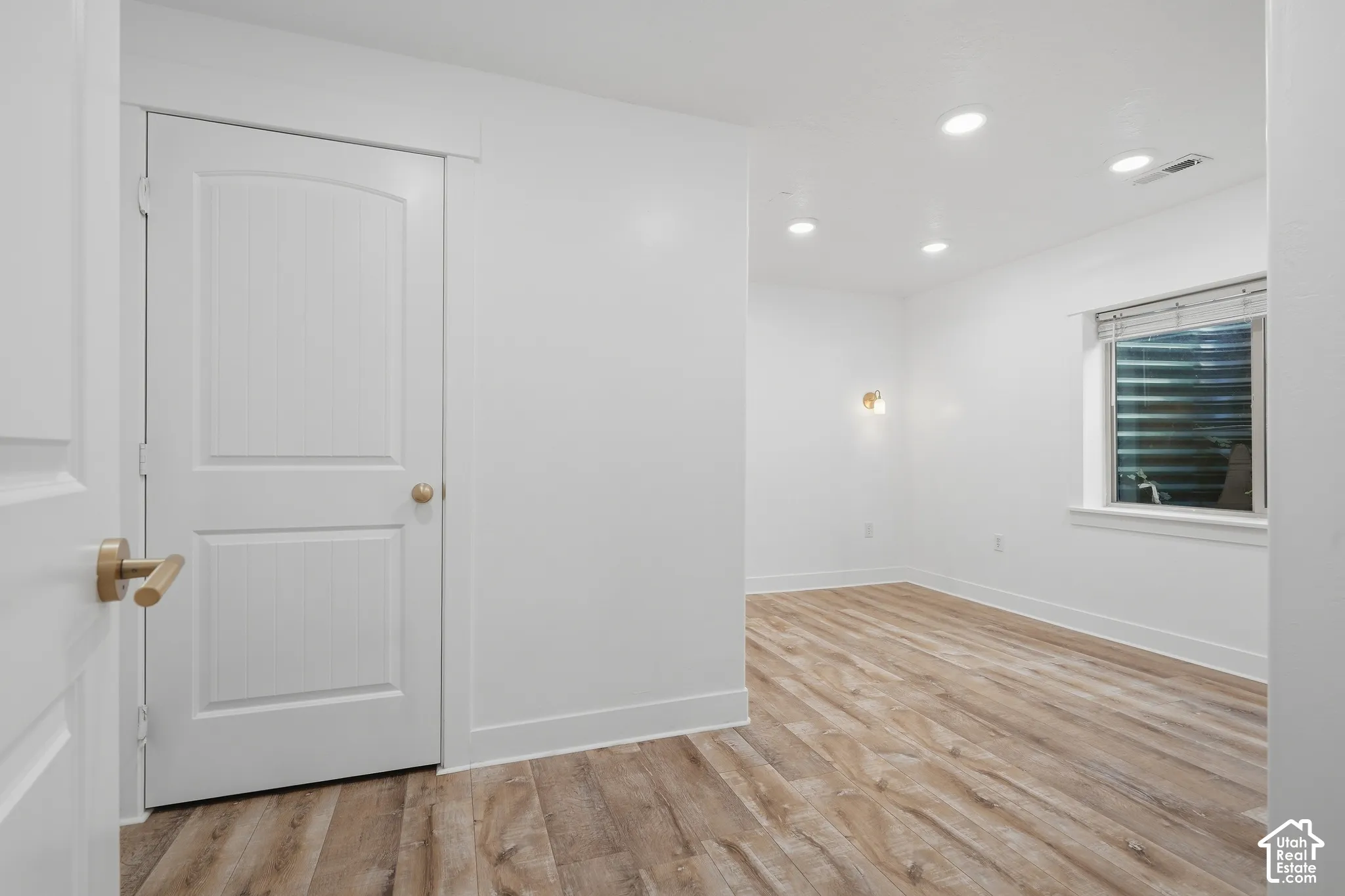 Bright, freshly renovated room featuring recessed ceiling lighting, wood-finish flooring throughout, and clean white walls