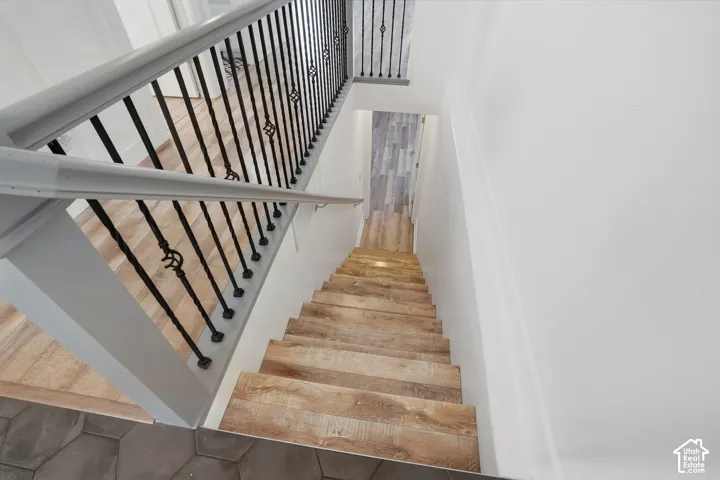 Hexagonal tile flooring, wood-finish stairs, white painted walls, wood-finish flooring, and wrought iron balusters with decorative elements