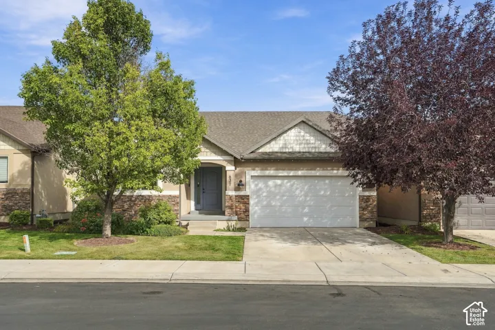 Neutral-toned siding with stacked stone accents, an attached garage, and a covered entry