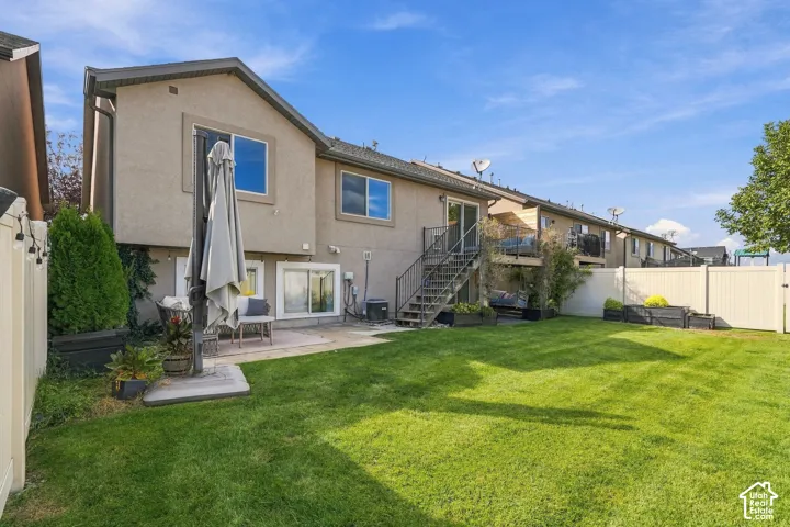 Expansive backyard featuring a meticulously manicured lawn, mature landscaping with privacy hedging, and a composite patio with integrated umbrella mount